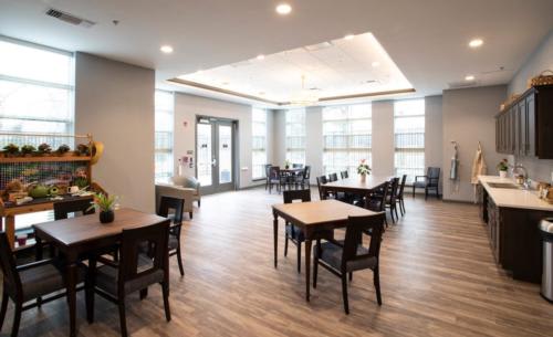 A modern dining room with wooden floors, featuring tables and chairs arranged in a spacious setting.