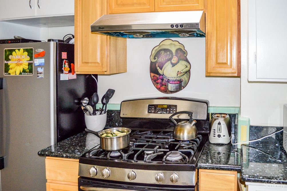 A kitchen with a stove and various cooking utensils on the countertop.