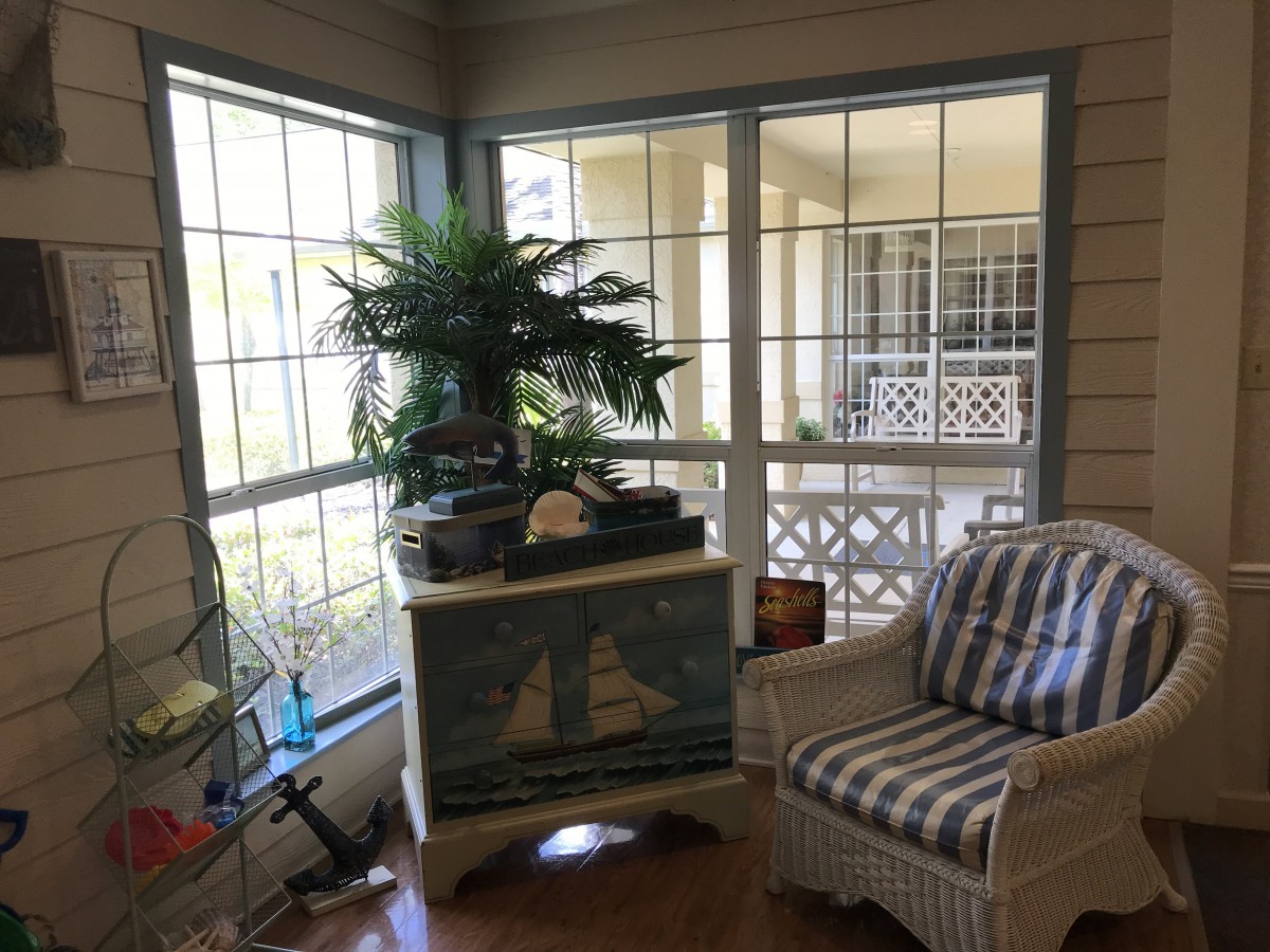A cozy sunroom with nautical decor and abundant natural light.