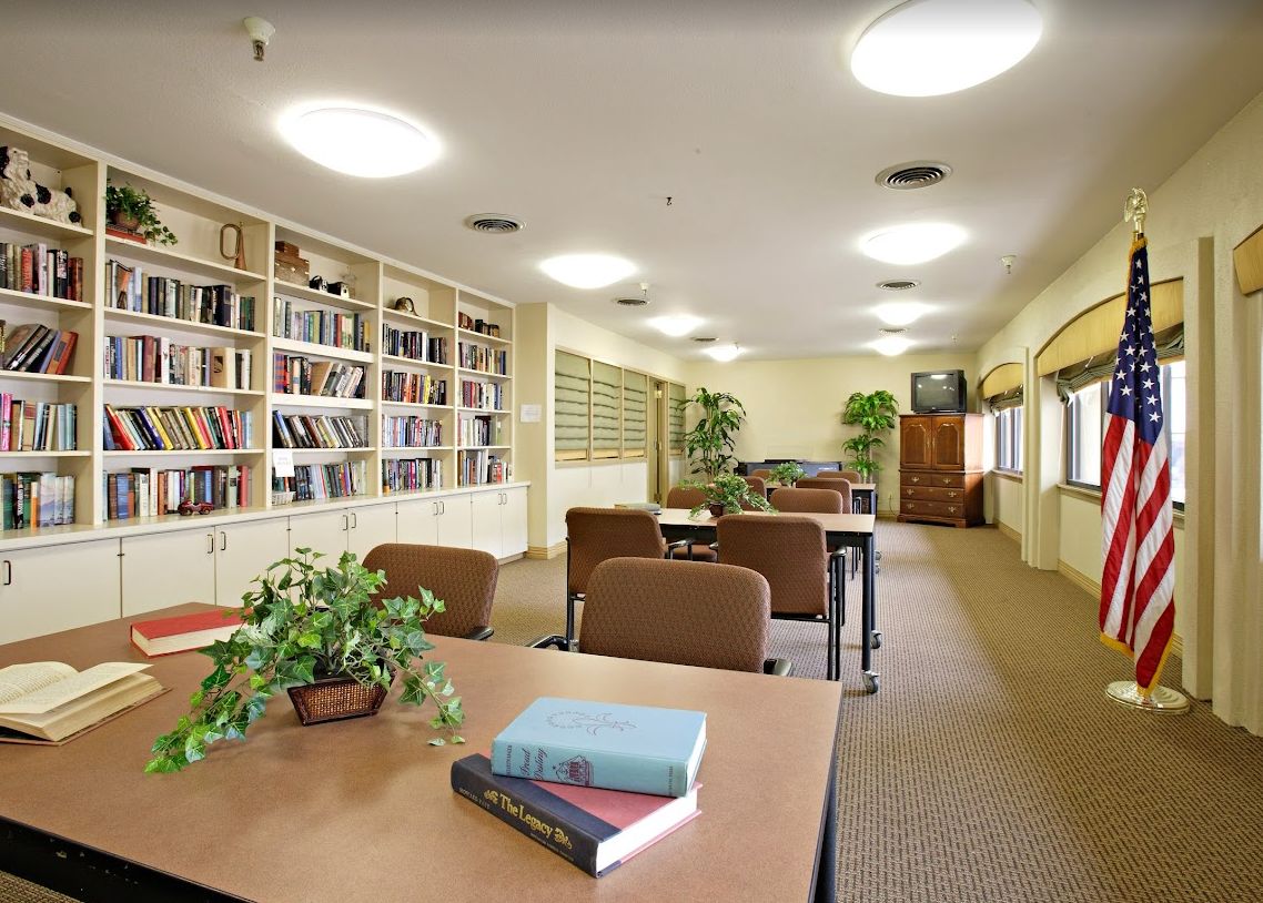 A quiet library study area with tables, chairs, and bookshelves.