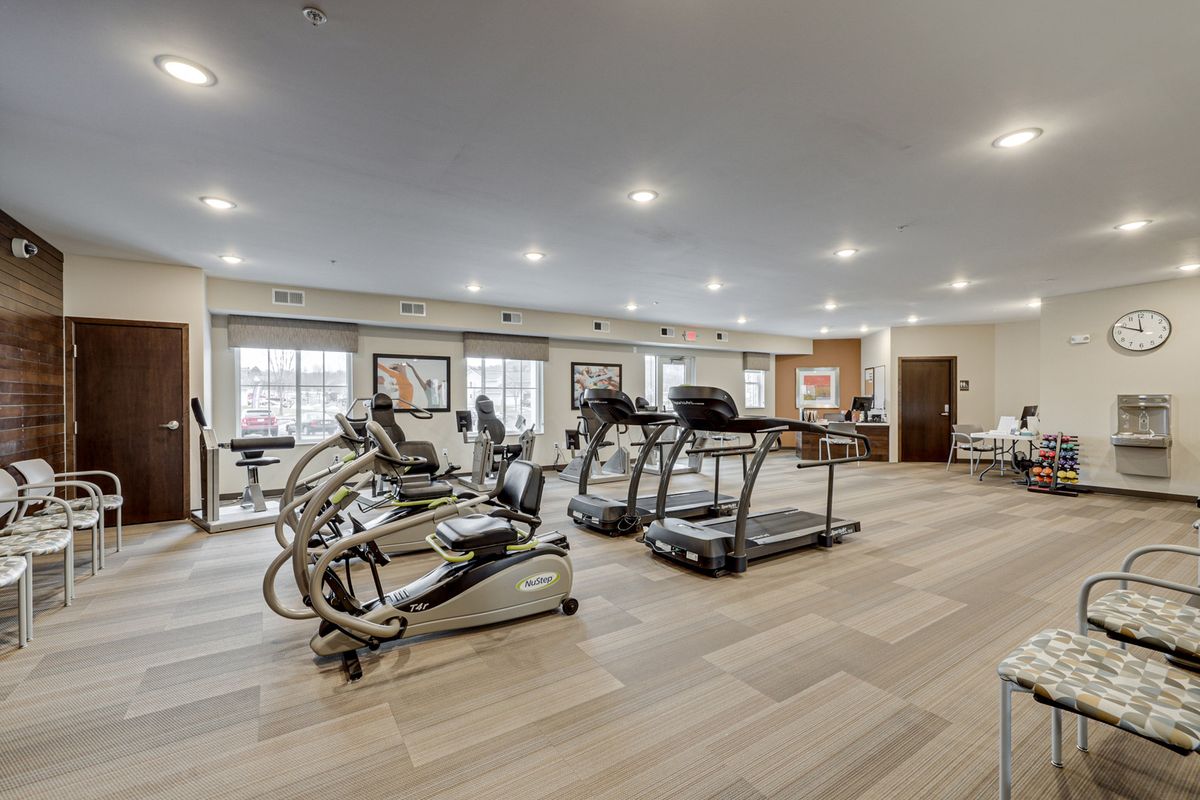 A modern and spacious gym with exercise equipment including treadmills and elliptical machines.