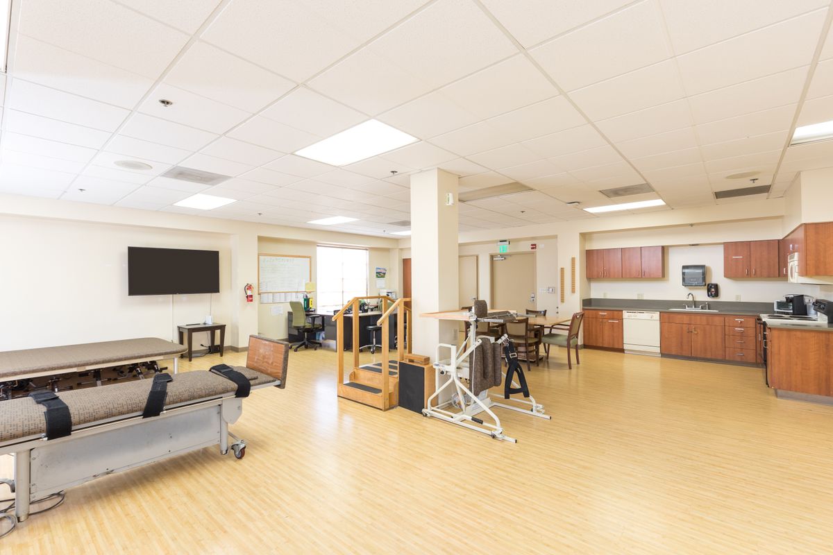 A bright and spacious physical therapy room with various exercise equipment and seating areas.