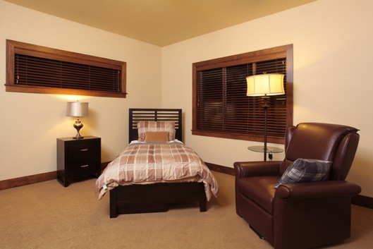 A cozy bedroom with a single bed, armchair, and warm lighting.
