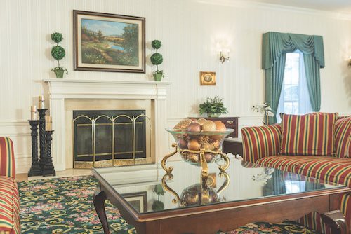 A cozy living room with a fireplace, elegant decor, and a glass-topped coffee table.