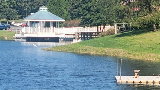 A serene view of a gazebo by the water, surrounded by lush greenery.