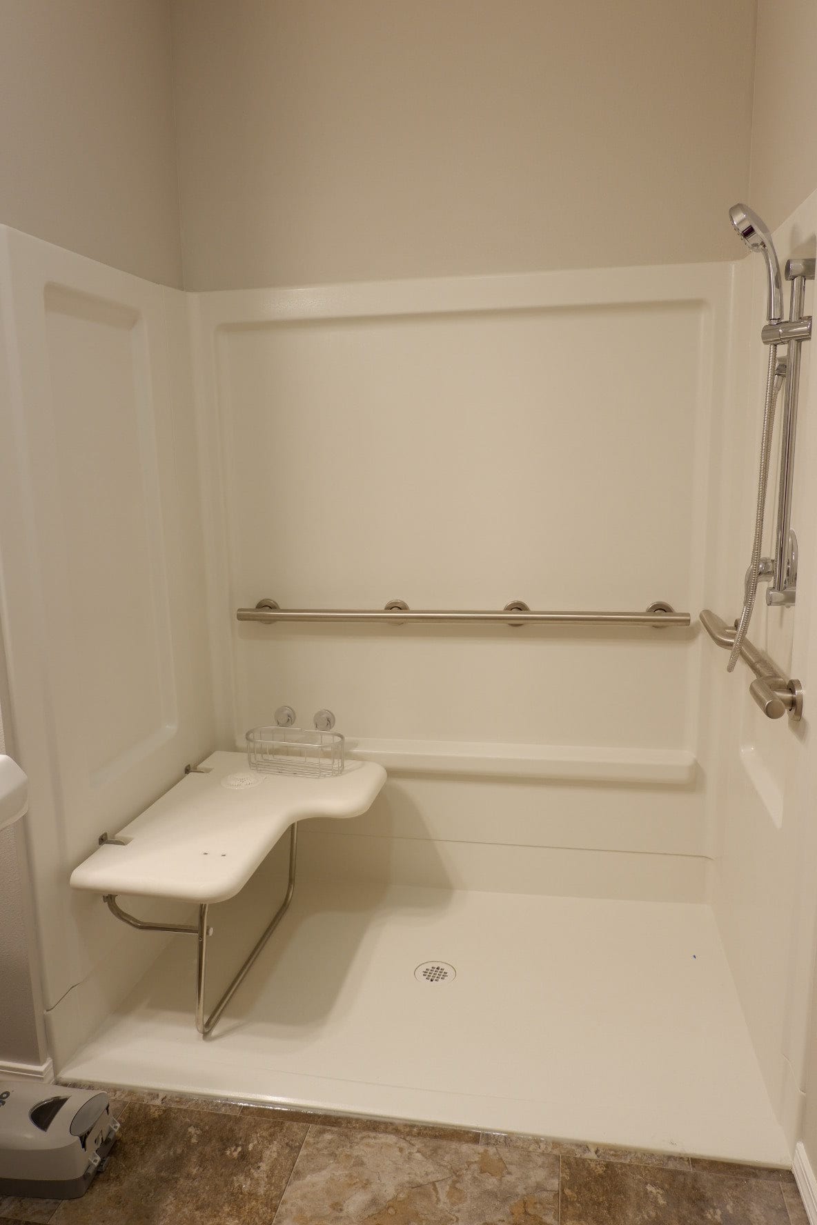 An accessible shower with grab bars and a folding seat for safety.