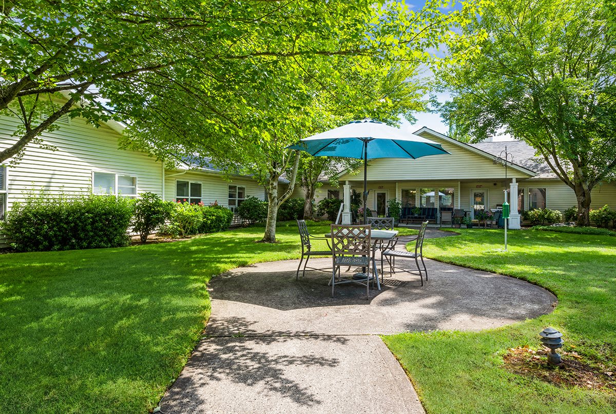 A tranquil garden patio with a shaded seating area on a sunny day.