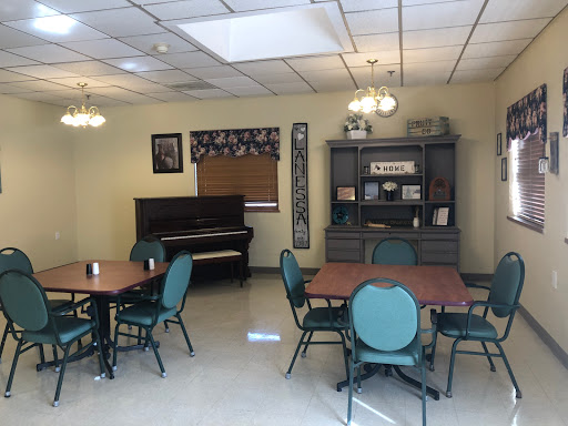 A cozy dining area featuring tables, chairs, and a piano, designed for community gatherings.