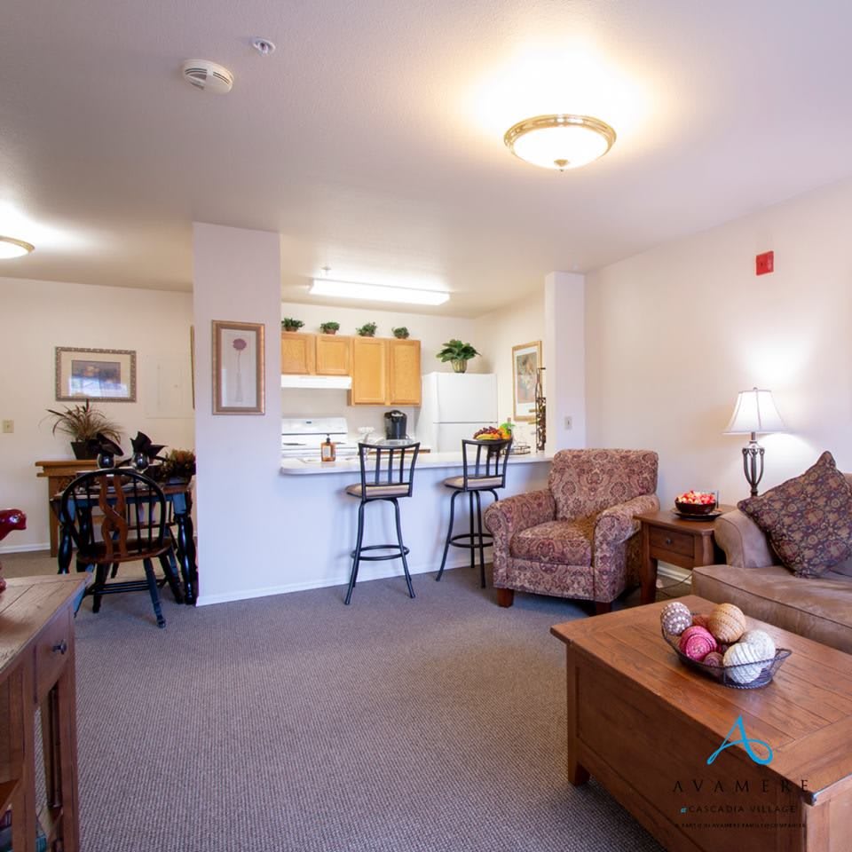 A cozy open-layout living space featuring a living room and adjacent kitchen with warm lighting.