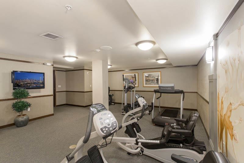 A modern indoor gym with exercise equipment including treadmills and elliptical machines.