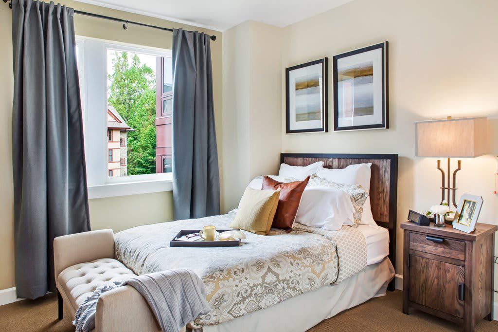 Cozy bedroom with single bed and stylish decor, featuring framed artwork and a window view.