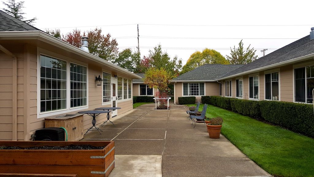 A courtyard between buildings with a paved walkway and planters.