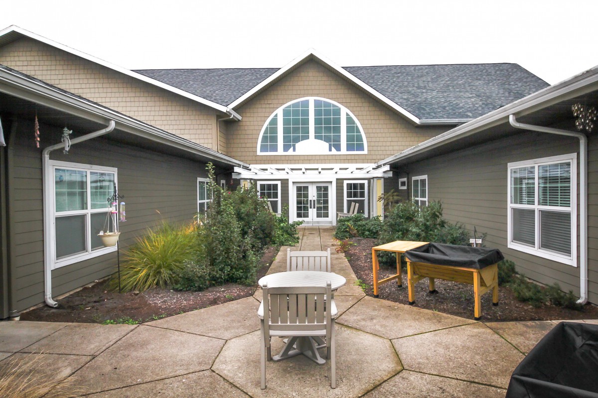 A view of a building's courtyard with patio furniture and surrounding greenery.