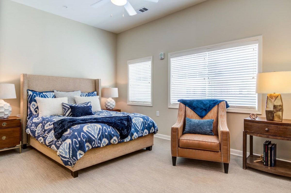 A cozy bedroom featuring a stylish bed with blue patterned bedding and a comfortable armchair by the window.