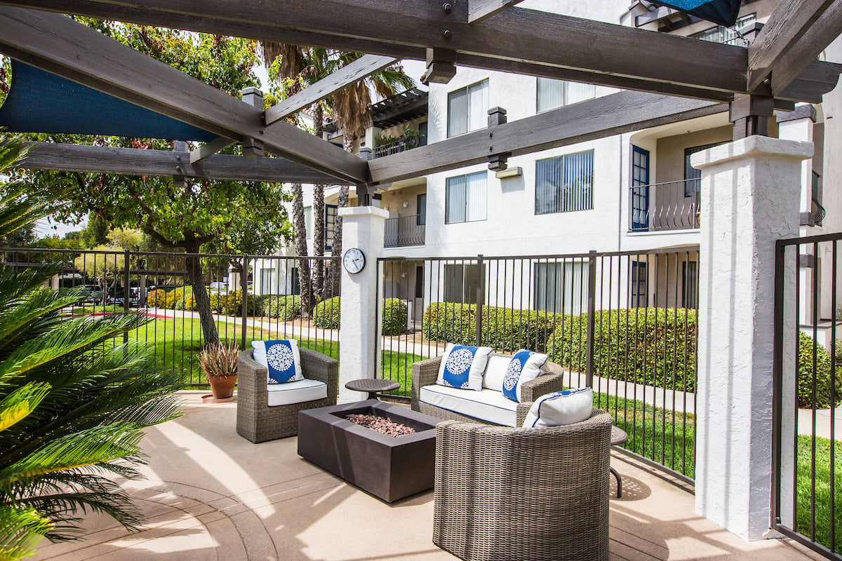 A cozy outdoor patio area with seating and a fire pit in an apartment complex.