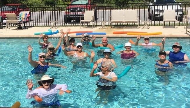 A group of people enjoying a fun day in the pool with water noodles.