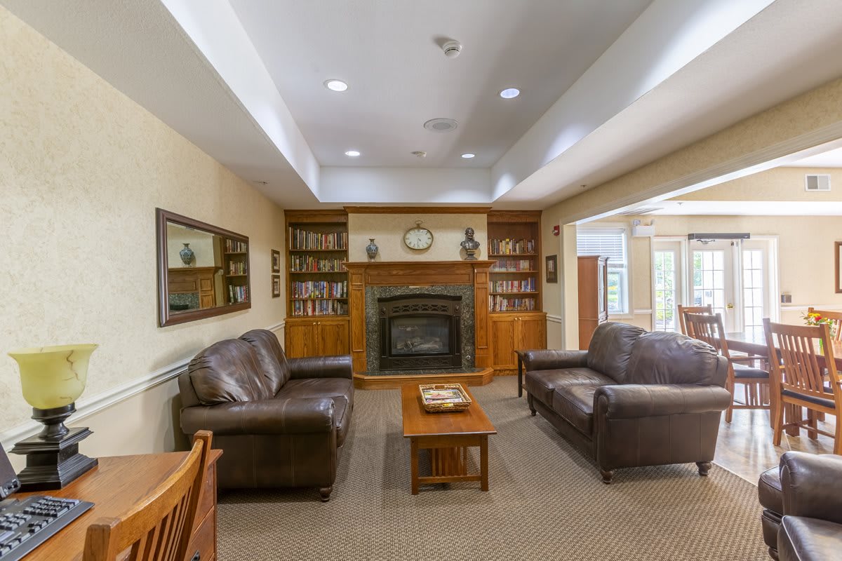 A cozy living room with leather sofas, a fireplace, and built-in bookshelves.