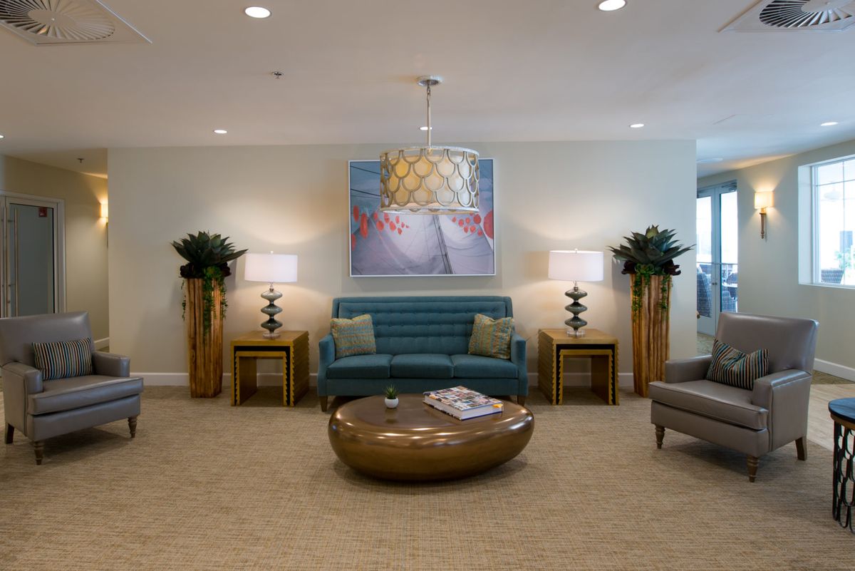 A modern living room with a central sofa, artwork on the wall, and elegant lighting.