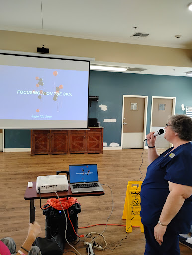 A speaker uses a microphone while presenting in front of a projection screen.