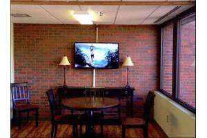 A cozy room interior featuring a brick wall, a mounted television, and a small table with chairs.