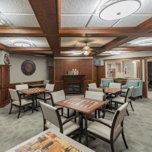 A cozy dining area with wooden accents, featuring multiple tables and chairs arranged neatly under modern lighting fixtures.