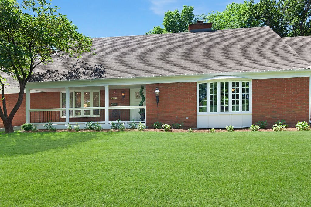 A brick house with a well-maintained lawn under a clear blue sky.