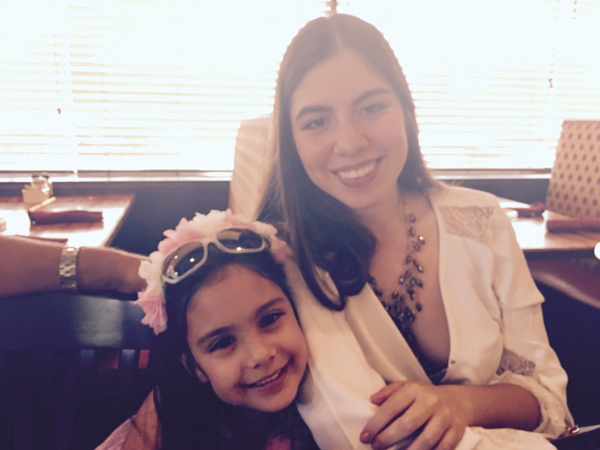 A mother and daughter smiling together indoors.