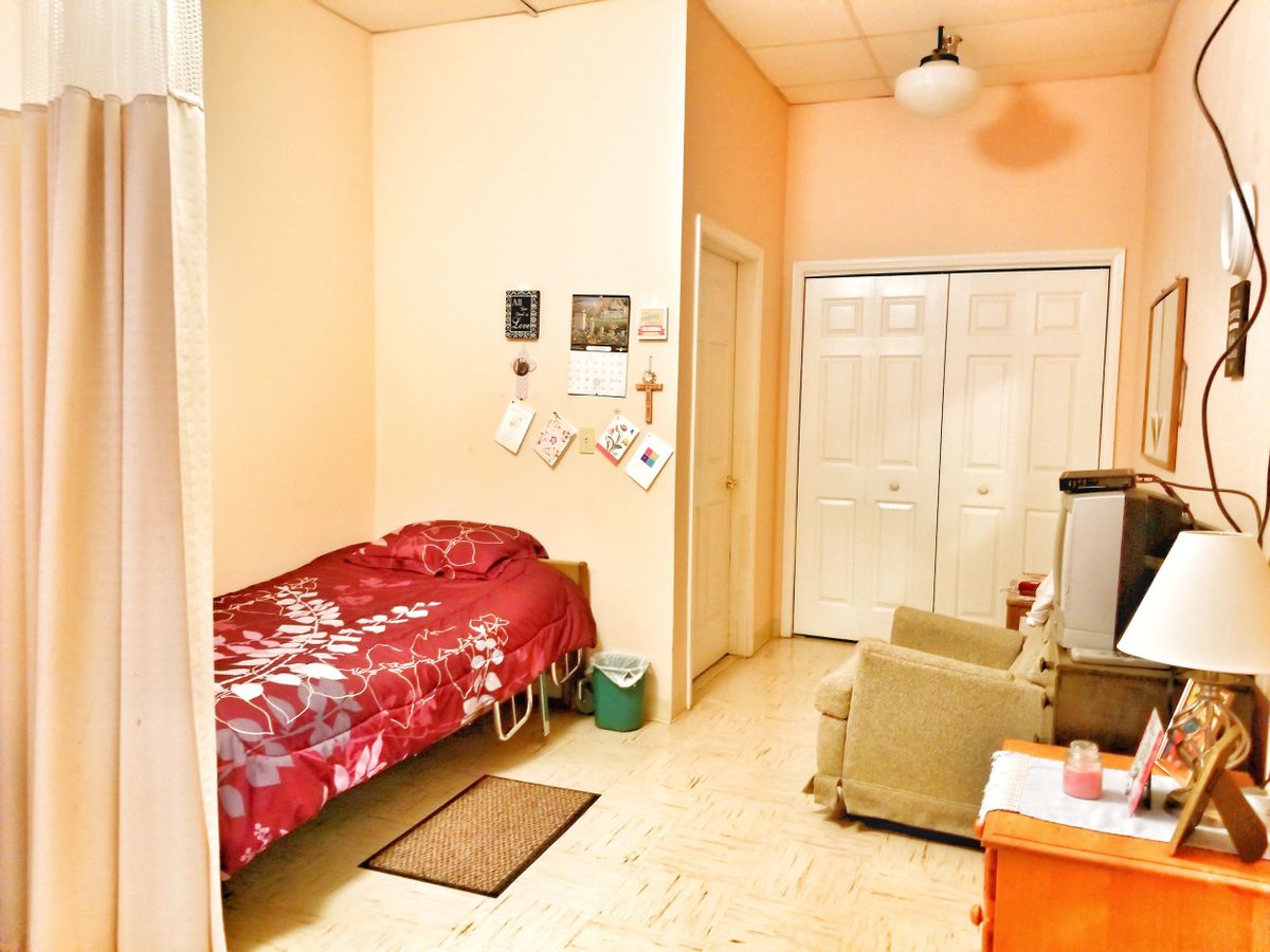 A cozy bedroom with a single bed, armchair, television, and wardrobe.