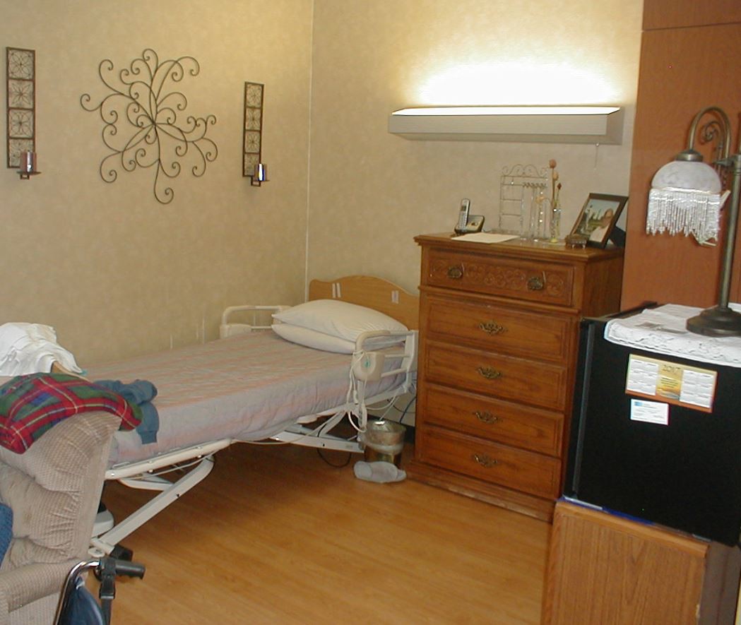 A cozy nursing home room featuring a bed and dresser.