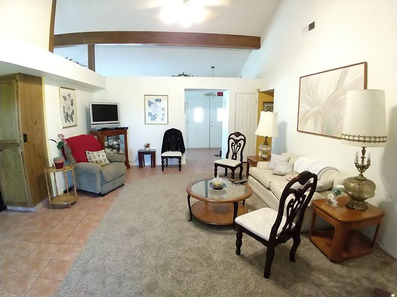 A cozy living room with a mix of classic and modern furniture, featuring a sofa, chairs, coffee table, and television.