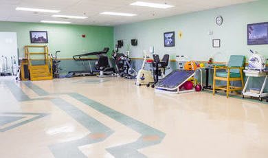 A spacious rehabilitation room equipped with various therapy and exercise machines.