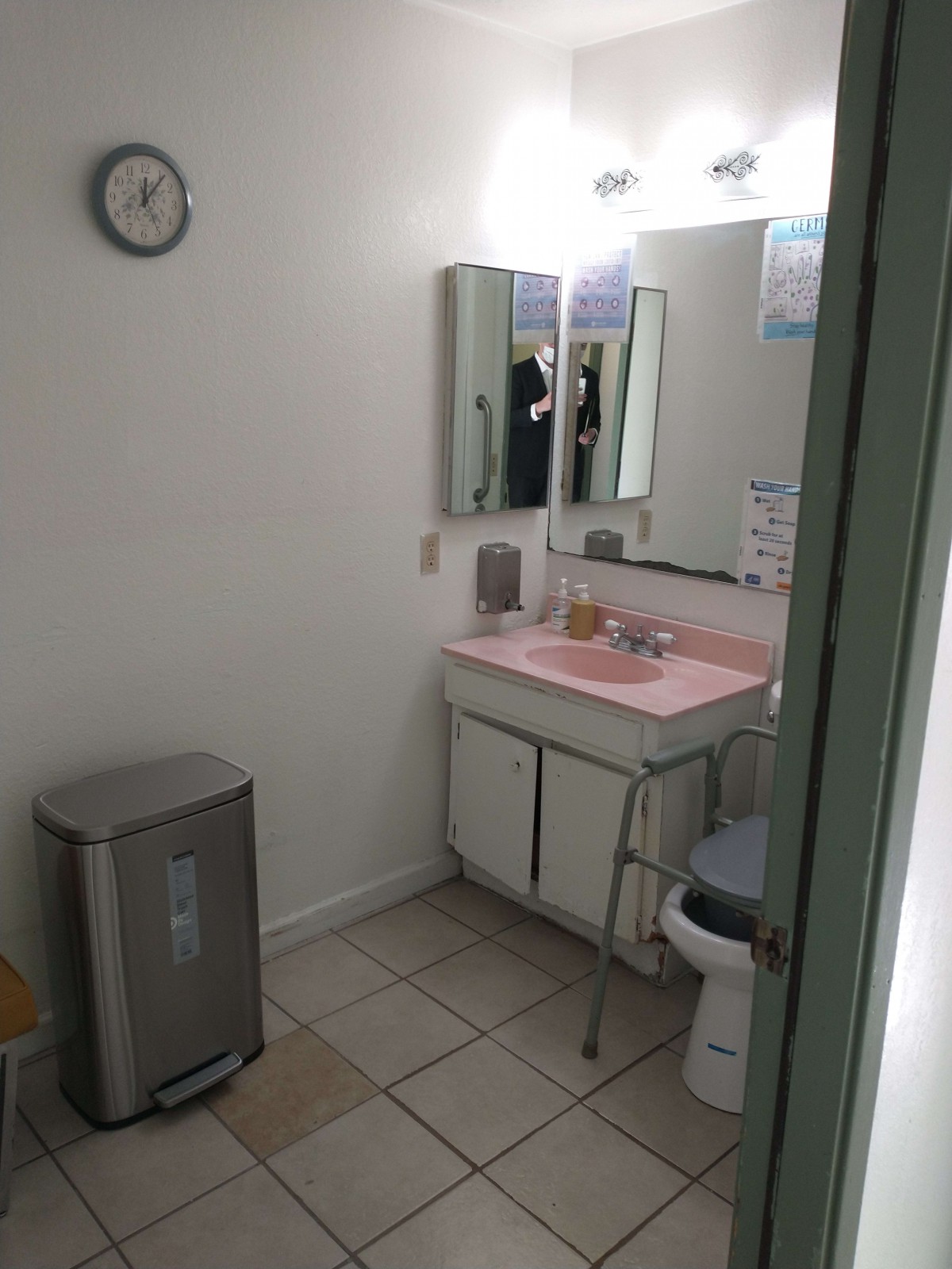 A small bathroom with a pink countertop and mirrored cabinet.