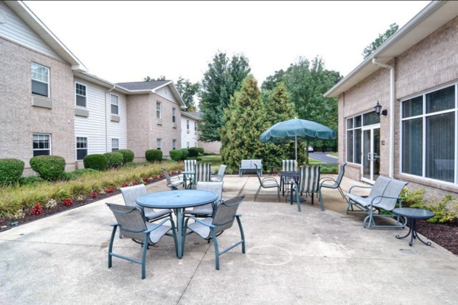 An outdoor patio area with tables, chairs, and an umbrella near a building.
