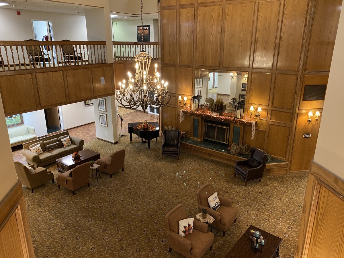 A spacious lobby with elegant wood paneling, a grand chandelier, comfortable seating, and a fireplace.