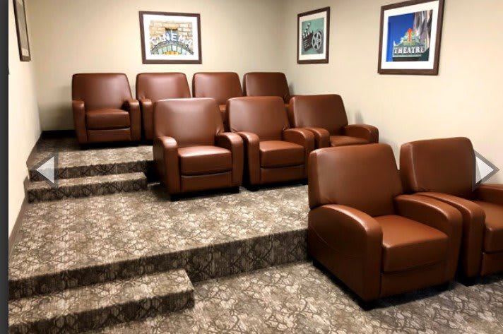 A cozy home theater with comfortable brown armchairs arranged in tiers.