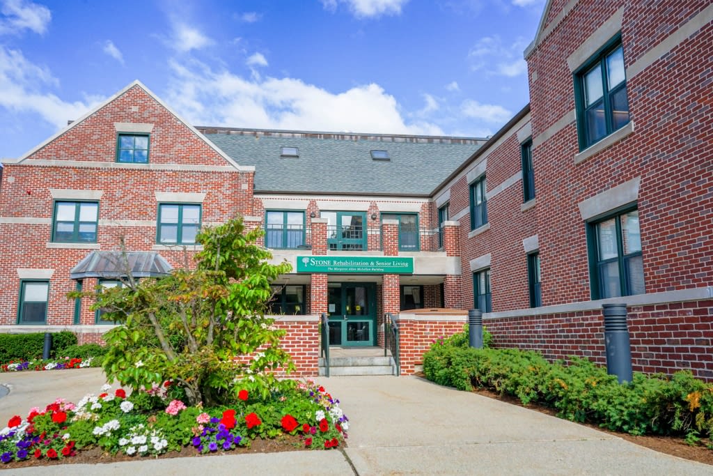 A brick building entrance with a garden and pathway.