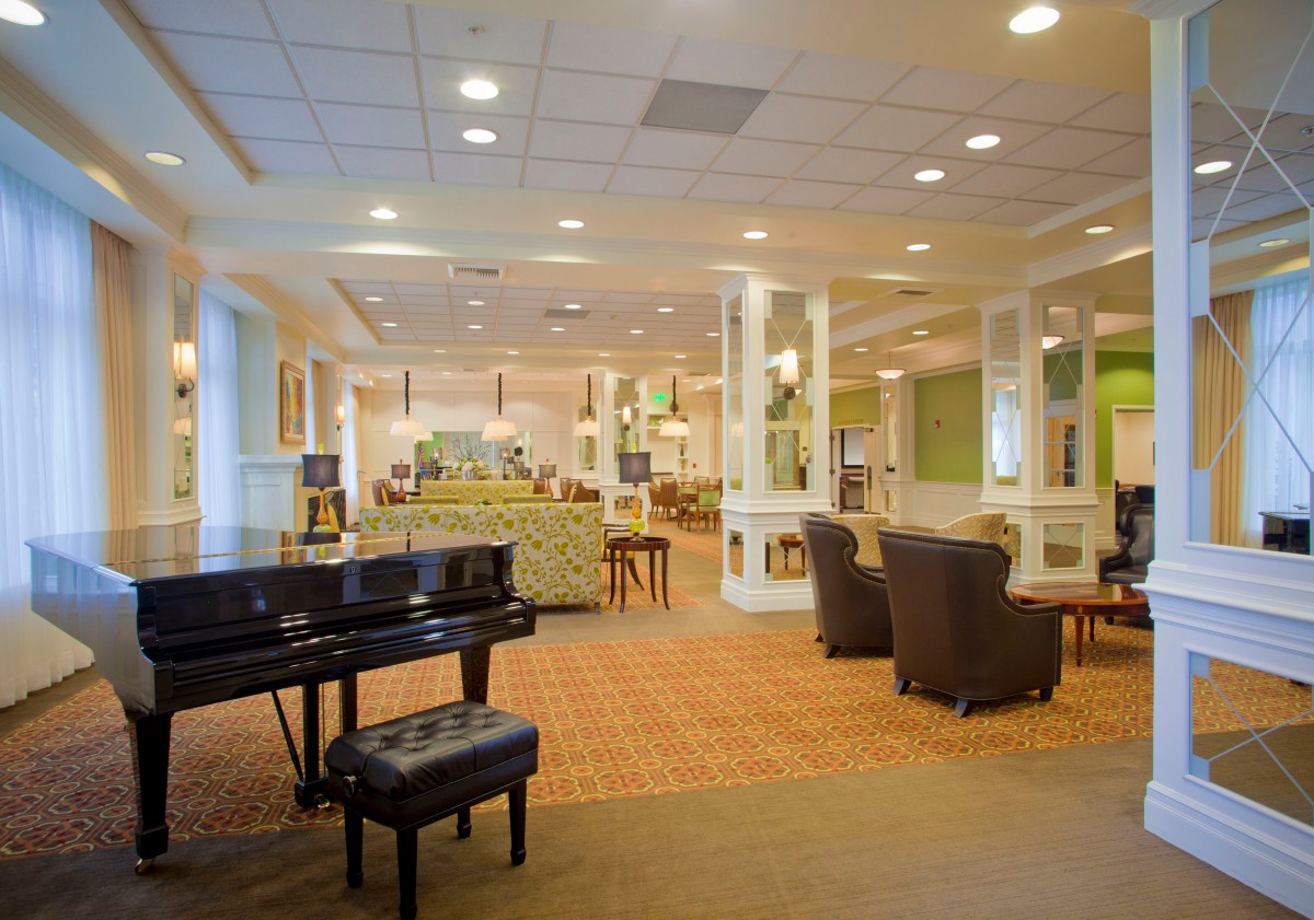 A spacious lounge area featuring a grand piano, comfortable seating, and ambient lighting.