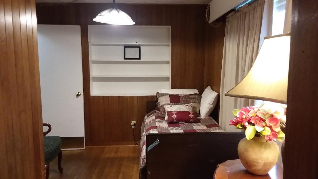 Cozy bedroom with wood paneling and a neatly made bed.