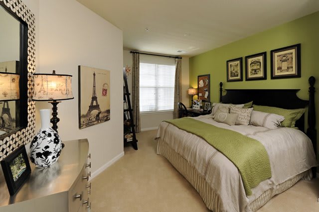 A cozy bedroom with a green accent wall, elegant decor, and a comfortable bed.