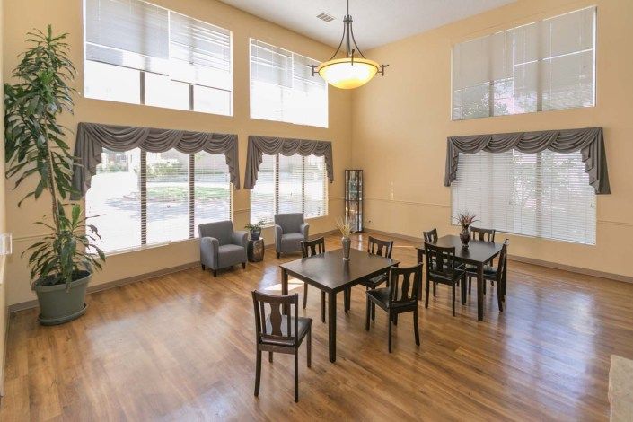 A bright dining area with multiple tables and chairs, featuring large windows that allow natural light to fill the space.