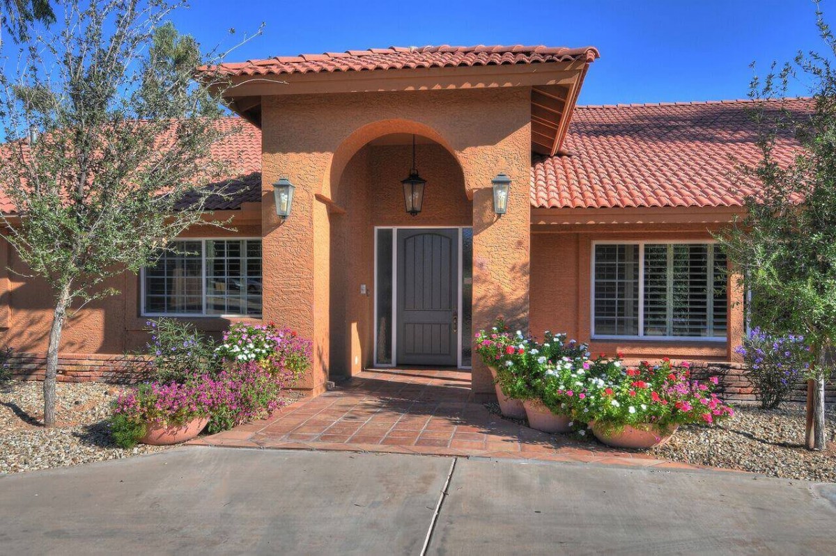 A welcoming entrance of a residential house with a well-kept garden and floral decorations.