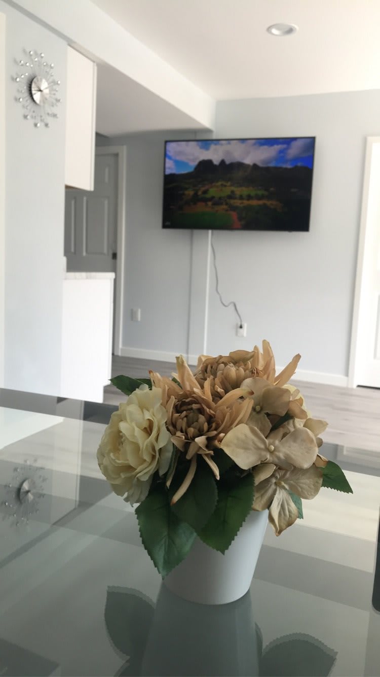 A modern living room with a decorative flower arrangement on the table and a wall-mounted TV.