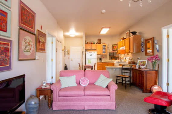 A cozy living room with a pink sofa and open kitchen layout.