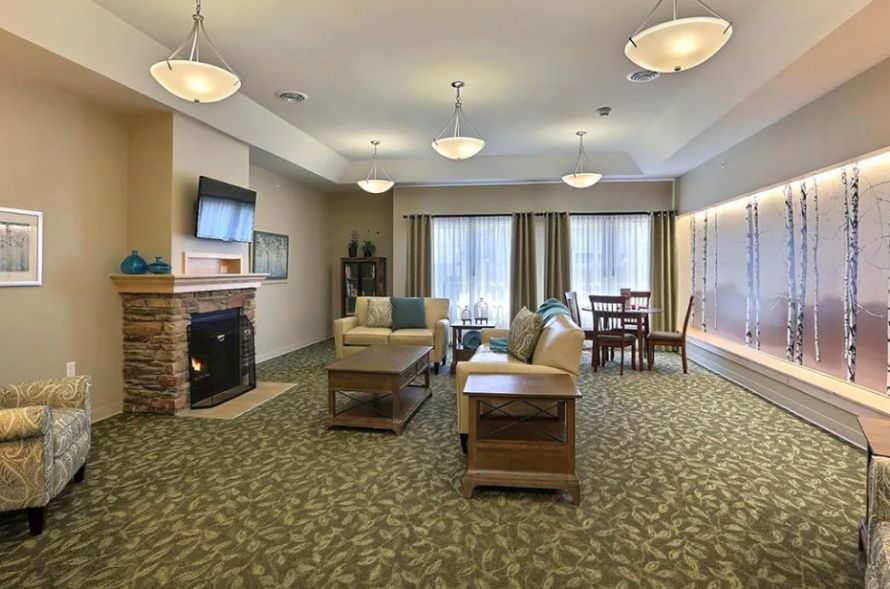 Spacious living room with modern furnishings, featuring a sofa, table, fireplace, and a wall-mounted television.
