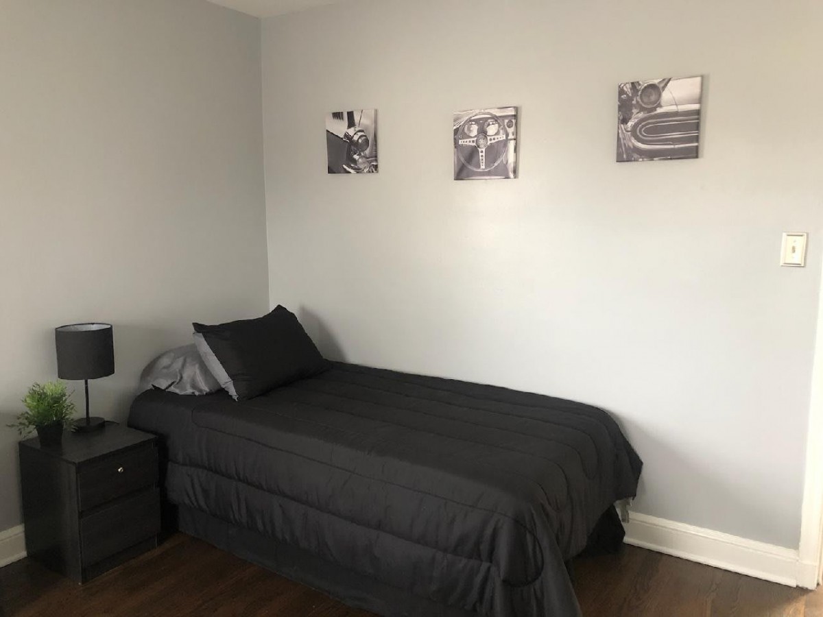A minimalist bedroom with a single bed, gray bedding, and wall art.
