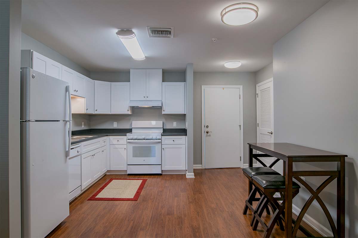 A modern kitchen with white cabinets and a small dining area.