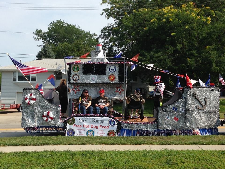 A decorated parade float featuring military themes and participants in a community event.