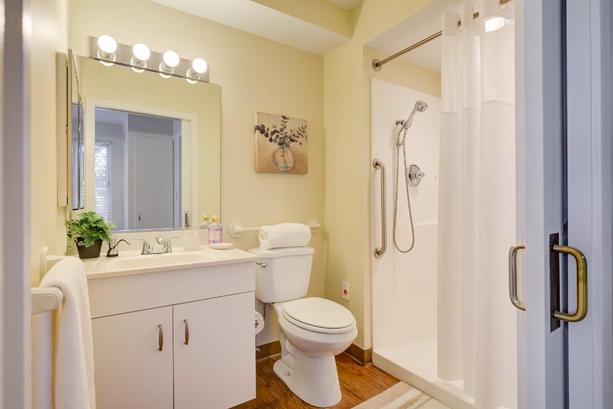 A modern bathroom featuring a shower, toilet, and sink with bright lighting and tasteful decor.