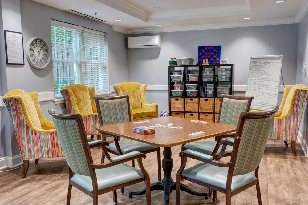 A cozy meeting room with a wooden table, chairs, and bookshelves.