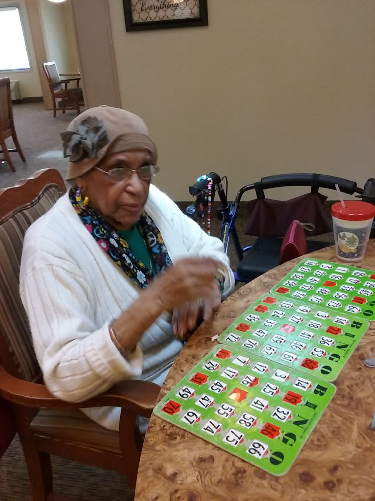 An elderly woman playing bingo indoors, enjoying a leisure activity.